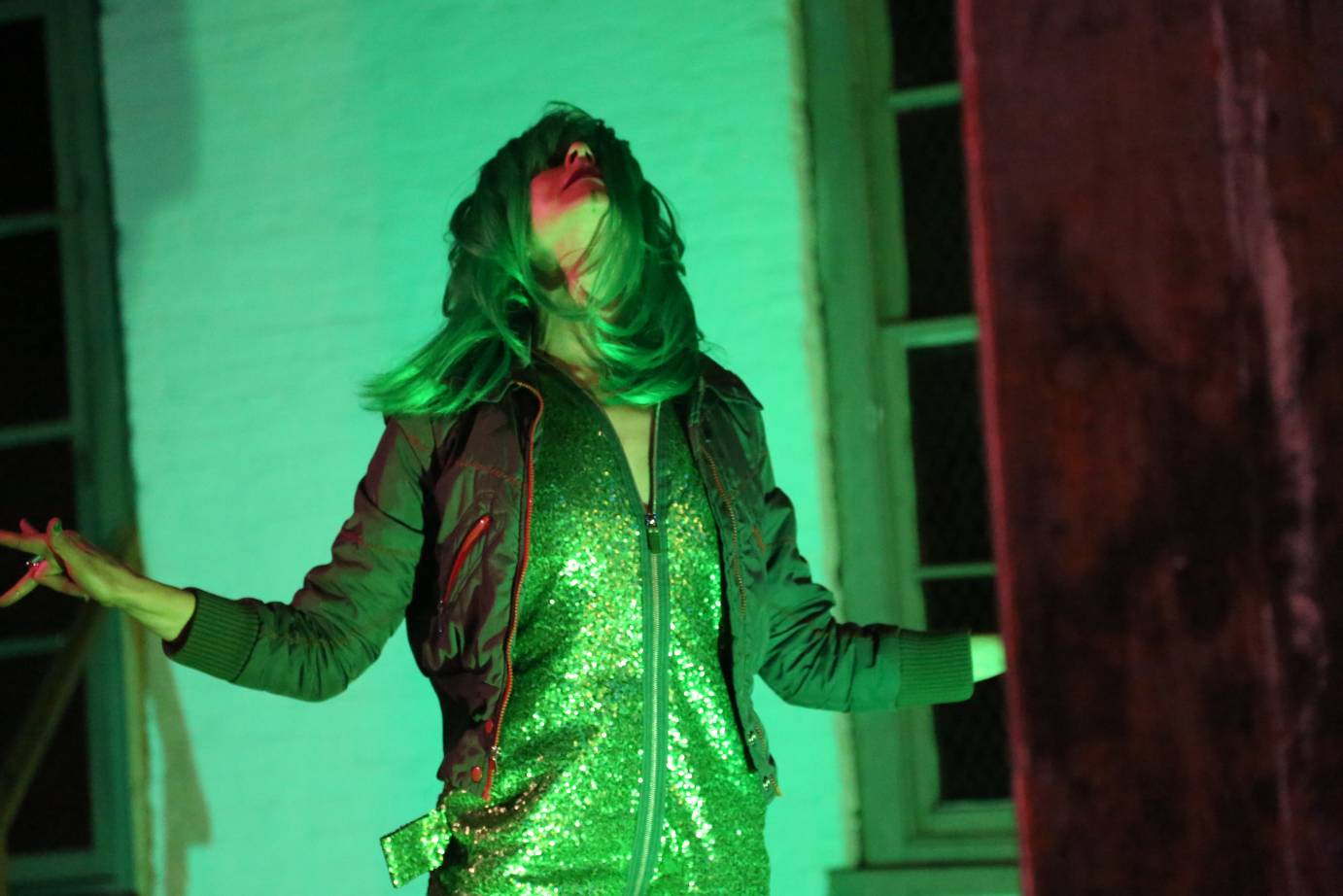 A woman in a green wig throws her head back